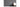 T3C button stuck on a dark grey wall above a shelf with a white vase