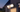 Solar Floodlight Cam on a house wall at dusk with both lamps lit