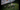 Colour night footage of a caravan and camping table on grass, lit by the spotlight