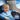 Smiling boy on a plane wearing blue BTH22, with 60-hour playtime and wired backup icons