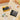 Yellow and black camera models on a picnic blanket with square prints and food